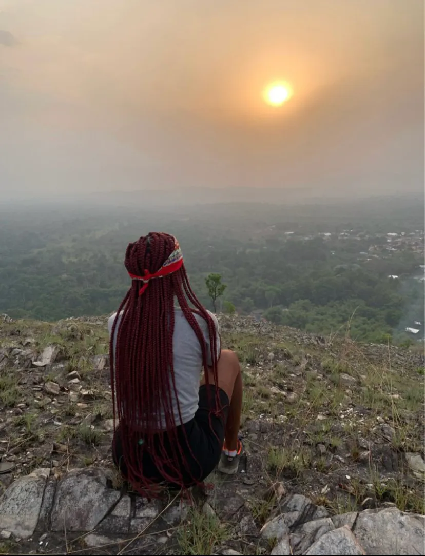 Photo of a young woman sitting on top of the mountain Afadjato in the Volta Region of Ghana. Photo by Jonathan Abayaa.
